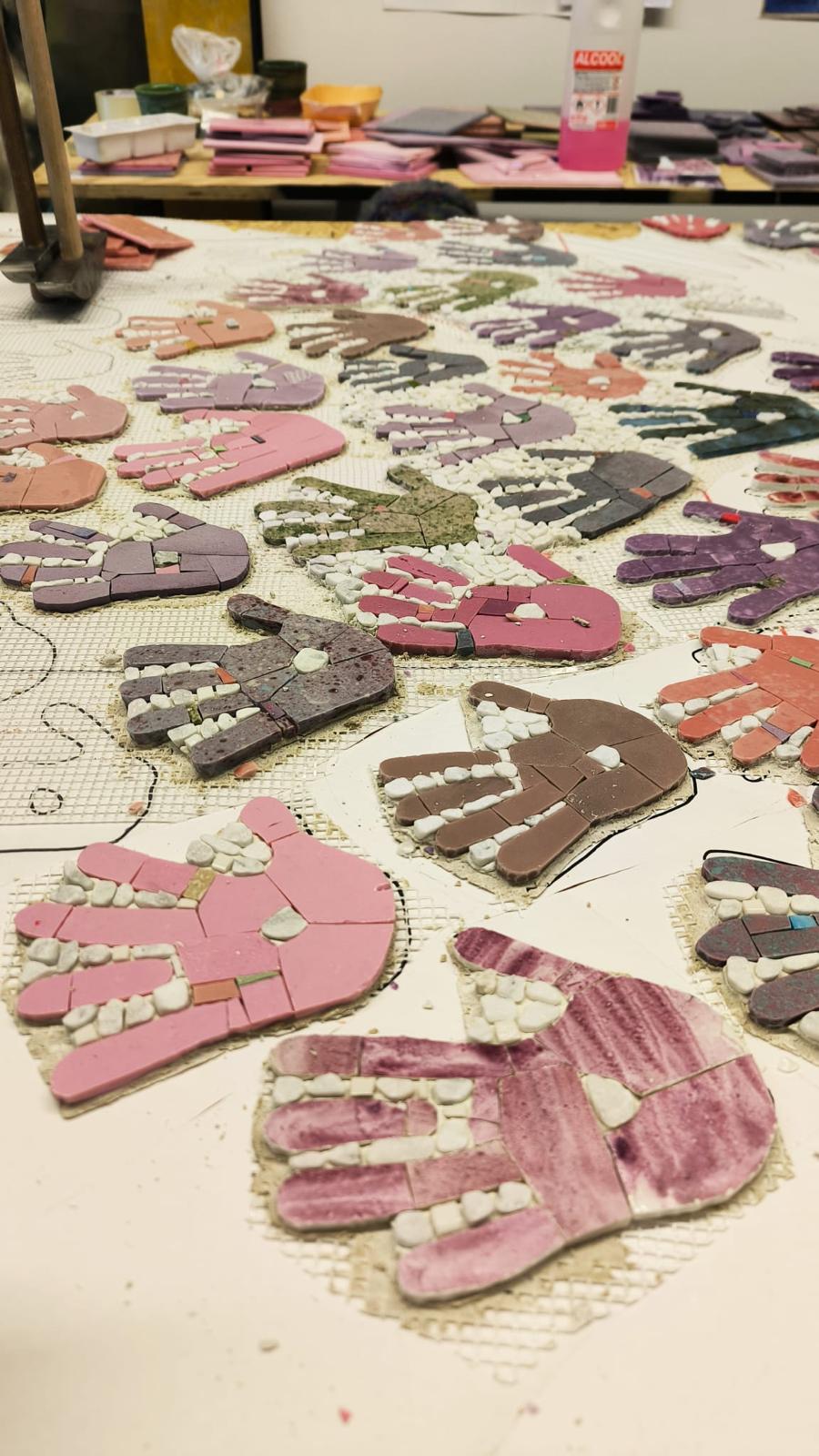 Dettaglio del mosaico in lavorazione con tessere a forma di mano.